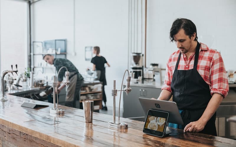 Cafe worker checks a tablet beside a counter payment terminal